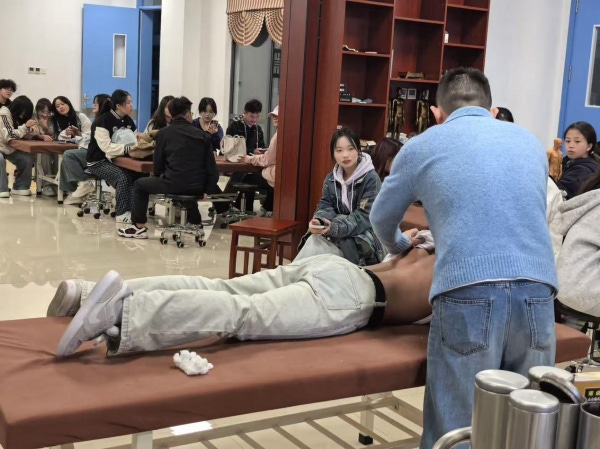 同学们分组进行拔罐实操练习，指导老师巡回纠正操作手法.png